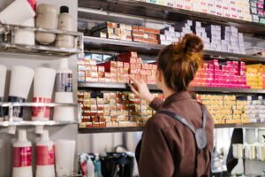 A hairstylist organizing vibrant hair color boxes on a shelf in a beauty salon.